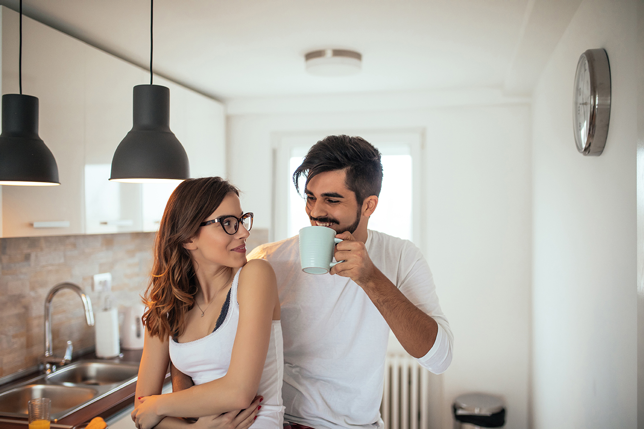 Adding sugar to his coffee Young couple having a romantic moment in the morning