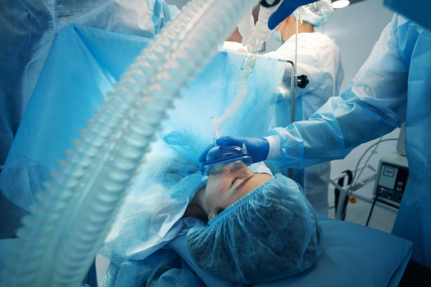 Doctor covering patient mouth and nose with oxygen supply mask Anesthesiologist providing supply of anaesthetic gas through mask to female patient during surgery