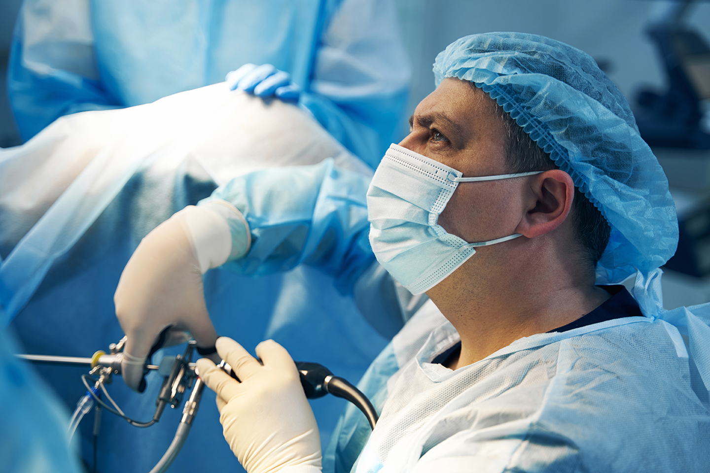 Face of surgeon in mask holding laparoscopic tool Close-up photo of male Caucasian surgeon with medical mask and laparoscope in hand