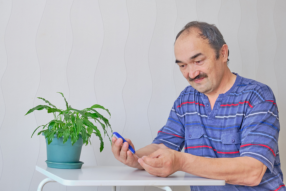Senior man checking blood sugar level Senior man checking blood sugar level at home