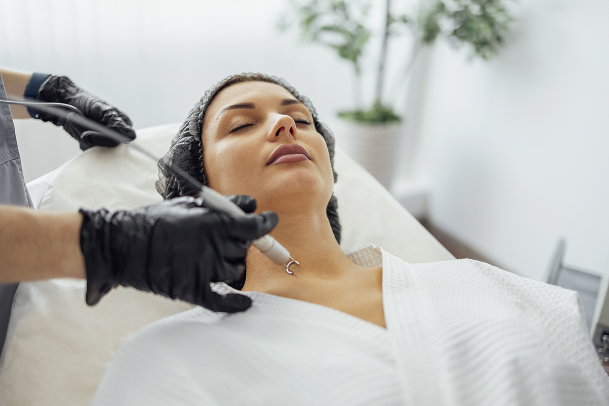 Beautiful caucasian young woman is doing a mole removal procedur Beautiful caucasian young woman is doing a mole removal procedure in a modern beauty cosmetic dermatological clinic. Skin moles treatment by laser method. Close up. Free space for text