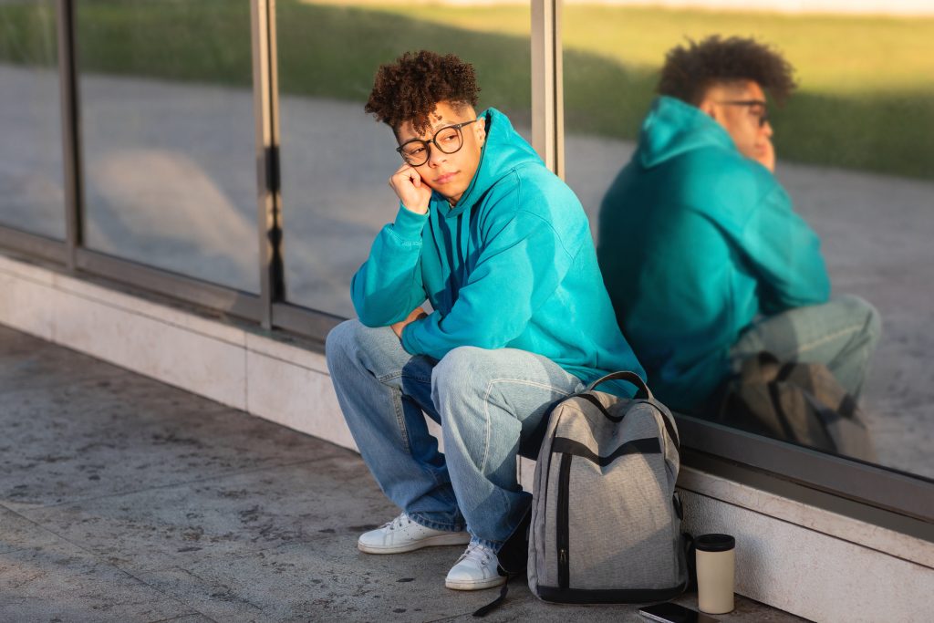 Young guy student sitting outside with reflection