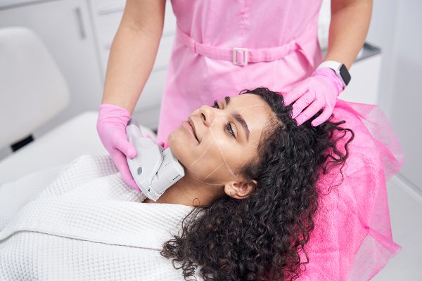 Relaxed lady lies with her eyes open while on the procedure of hardware cosmetology