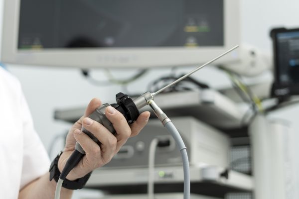 Man holds a medical endoscope, on the background of medical equipment, monitor, selective focus. Detailed health studies, modern technologies in medicine.