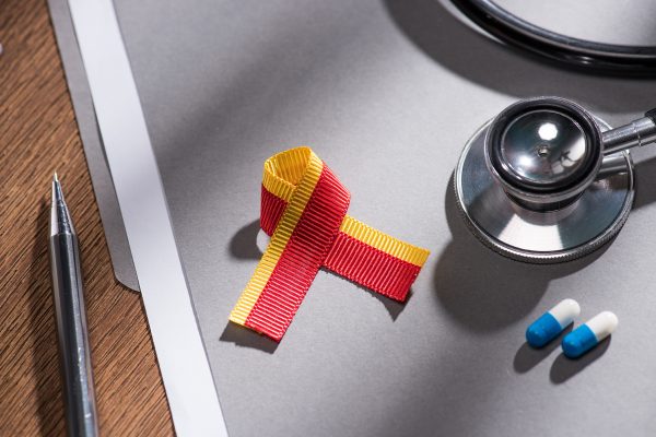 selective focus of ribbon, stethoscope, pills and folder with pen on table, world hepatitis day