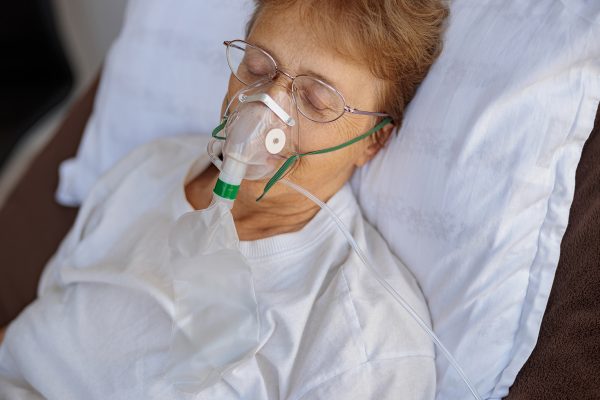 Senior patient in breathing mask lies in the ward during treatment for Covid-19. High quality photo