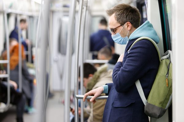 Ill man in eyeglasses feeling sick, wearing protective mask against transmissible infectious diseases and as protection against the influenza in public transport. New coronavirus 2019-nCoV from China