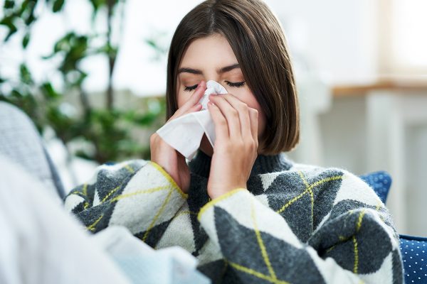 Picture of a teenager sneezing in a tissue in the living room
