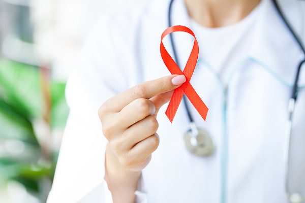 Woman hand holding red ribbon HIV, world AIDS day awareness ribbon